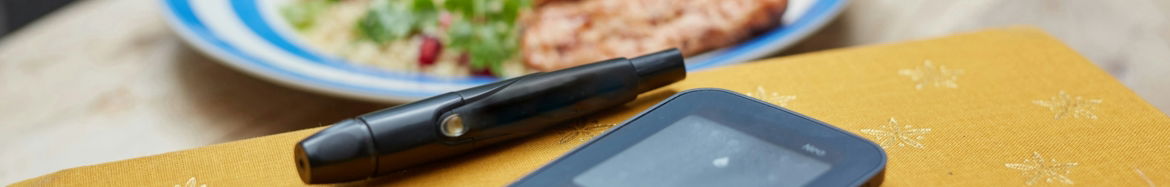 a plate of food and a Glucometer on a table